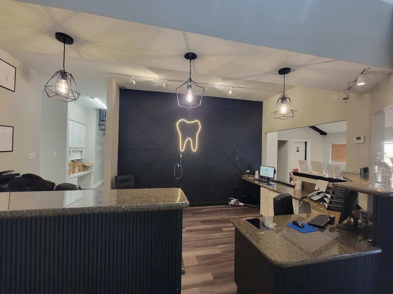The Harwood Family Dental reception desk with tooth logo wall