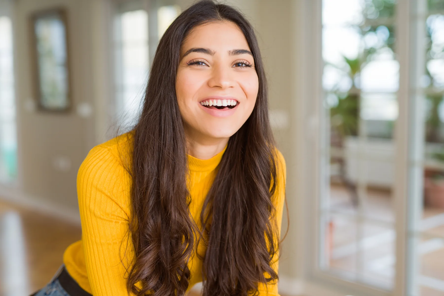 Smiling young woman in a yellow sweater indoors